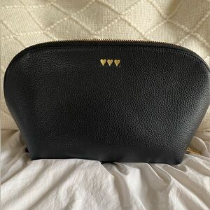 Black pebbled leather Cuyana cosmetic pouch with three gold hearts. Large size